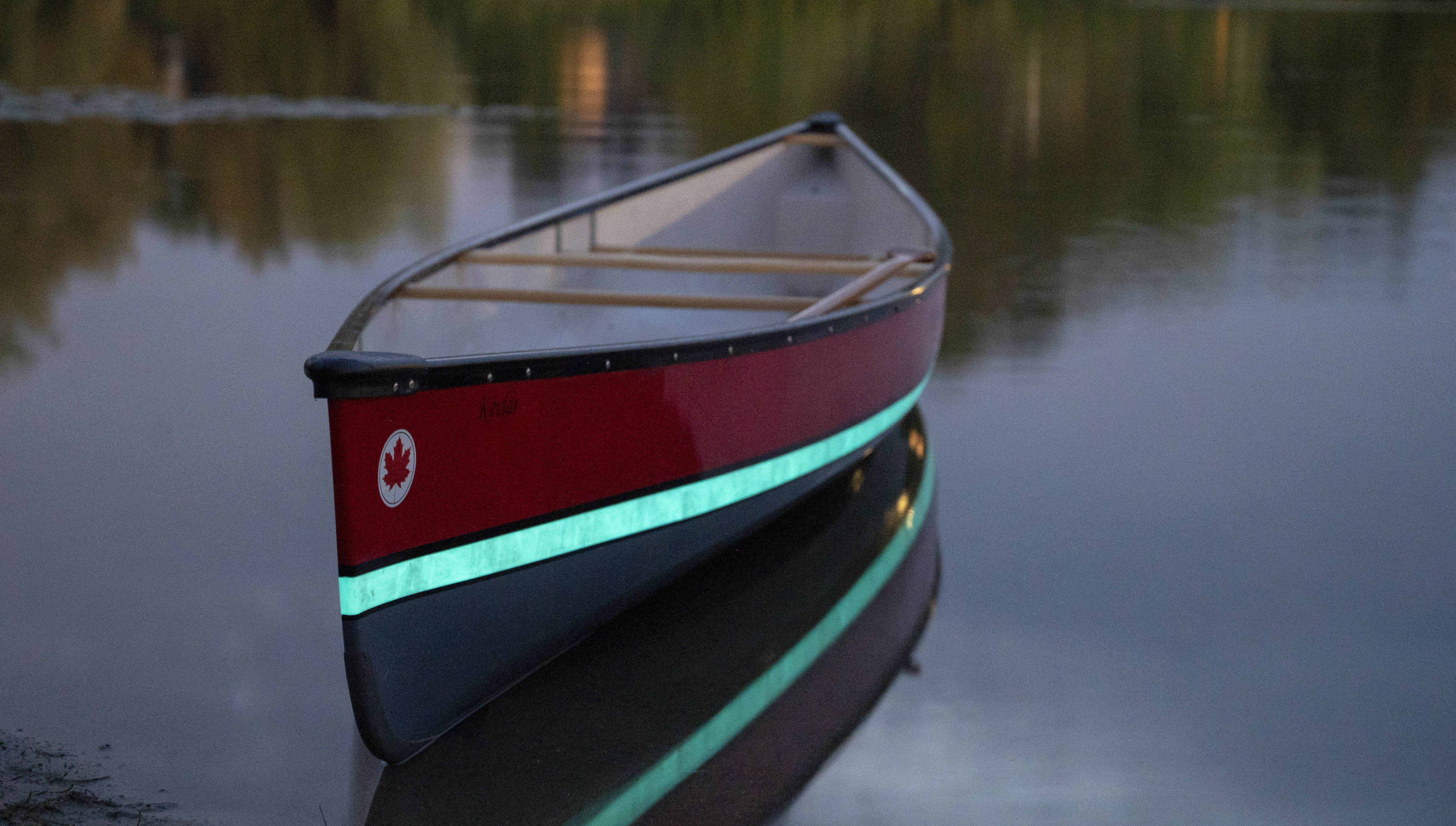 Naomi, the Creative Director paddling in a glowing canoe on dark waters